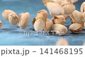 Pistachios fall and bounce across a blue table in super slow motion 141468195