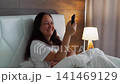 Woman Relaxing Bed Hotel Room Remote Control 141469129