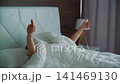 Woman relaxing on bed holding coffee cup in modern apartment 141469130