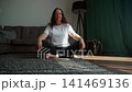 Woman stretching arms overhead seated on floor in living room 141469136