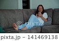 Woman relaxing on couch using smartphone at home 141469138