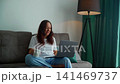 Woman working on laptop while sitting on couch in modern apartment 141469737