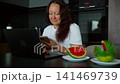 Woman using smartphone in modern kitchen with fresh watermelon 141469739