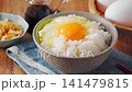 Egg over rice: A breakfast of white rice and a raw egg served in a bowl. 141479815