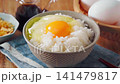 Egg over rice: A breakfast of white rice and a raw egg served in a bowl. 141479817