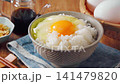 Egg over rice: A breakfast of white rice and a raw egg served in a bowl. 141479820