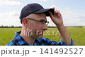 Thoughtful man stands in green field looking toward horizon. Vertical video symbolizes vision, leadership, strategic thinking and confidence while planning for future success. 141492527