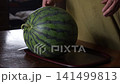 A woman cutting a watermelon in half 141499813