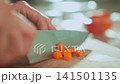 Woman hand dicing carrot with kitchen knife on wooden cutting board 141501135
