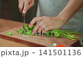 Woman hands were chopping fresh cilantro on a wooden cutting board 141501136