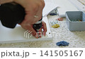 Hand assembling furniture with screwdriver, screws, and tools on carpeted floor 141505167