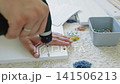 Hand using screwdriver to assemble furniture with screws and tools on carpet 141506213