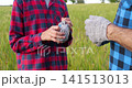 Farmer hands work gloves to child in wheat field before starting daily tasks. Symbolic family moment represents responsibility, trust, practical learning and future generation of agriculture. 141513013