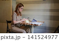 Woman checking smartphone with floor plans at cafe 141524977