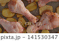 Top down view of seasoned raw chicken legs and potato slices 141530347