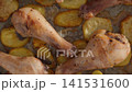 Roasted chicken drumsticks with golden brown potatoes on baking paper 141531600