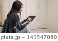 一位女士正在平板電腦上瀏覽一個金融投資網站。 141547080