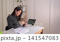 一位女士一邊在平板電腦上查看股票價格，一邊思考投資事宜。 141547083