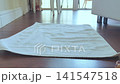 Woman places her bare feet on a white towel on a wooden floor, highlighting the texture and indoor environment with natural light streaming in 141547518