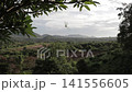 Scenic view of green mountain valley and tropical forest framed by leaves on top. Panoramic nature viewpoint landscape. 141556605