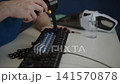 Detailed process of technician using portable electric air blower to clean switches of dirty mechanical keyboard after removing keycaps for deep maintenance. Shooting in slow motion 141570878