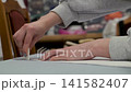 Hands gently place small white object on flat surface. Fingers carefully position item with precision. Soft lighting highlights delicate action. Background blurred, focusing on task at hand 141582407