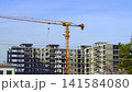 Video footage from a construction site where a yellow tower crane is being used to erect a multi-story building. The raised hook and free slings swing, and the boom swings toward the loading area 141584080