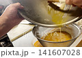 Prepare the rolled omelet by straining the beaten eggs through a sieve. 141607028