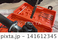 Close-up of hand in work glove inserting a drill bit into a hammer drill chuck. Construction and repair tools concept. 141612345