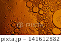 Orange liquid with bubbles of various sizes slowly floating and merging in a macro shot 141612882