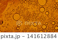 Orange liquid with bubbles of various sizes slowly floating and merging in a macro shot 141612884