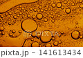 Orange liquid with bubbles of various sizes slowly floating and merging in a macro shot 141613434