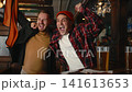 Friends cheering in pub during match. Guys celebrating goal raising orange scarf above head 141613653