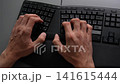 Top view of male hands typing on black ergonomic keyboard placed on gray office desk, illustrating concept of modern workflow, business communication, computer programming tasks, slow motion. 141615444