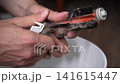 Process of maintenance of household appliance, male hands using cutting tool to remove accumulated dust, long hair, animal fur from very dirty vacuum cleaner roller brush. Shooting in slow motion. 141615447
