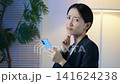 A middle-aged woman is troubled in a dark room, looking at her smartphone. Anxiety, worry, social media, apps, questions, dissatisfaction, disappointment, depression. 141624238