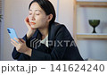 A middle-aged woman is troubled in a dark room, looking at her smartphone. Anxiety, worry, social media, apps, questions, dissatisfaction, disappointment, depression. 141624240