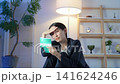 A middle-aged woman looks depressed in a dark room while looking at her bankbook. Savings, anxiety, worry, bank, household finances, investment, asset management, prices, tax increases. 141624246