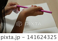 小型の鉛筆削りを使って鉛筆を削る子供の手元 141624325