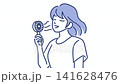 A woman who cools down with a portable fan 141628476