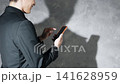 A man using a smartphone and his silhouette. Keywords: SNS, app, email, video, serious, anxiety, worry, fraud. 141628959