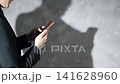 A man using a smartphone and his silhouette. Keywords: SNS, app, email, video, serious, anxiety, worry, fraud. 141628960