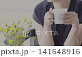 A woman drinking coffee at an open-air cafe. 141648916