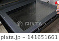 Cleaning process of dirty kitchen oven door glass panel with spray bottle and cleaning solution application by person hand in home kitchen setting. 141651661