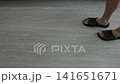 Person legs slowly walk on floor wearing black rubber slide sandals, close-up view of feet movement indoors, casual footwear fashion, comfortable house shoes 141651671