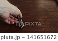 Metal silver knife with textured handle is moved on dark wooden cutting board, followed by brief hand interaction indicating item removal or placement, emphasizing kitchen tool 141651672