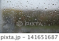 Raindrops cling to clear window glass, creating a blurred view of outside, showcasing quiet beauty of a rainy day. 141651687