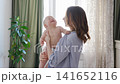 Mother holds baby and shares smiles in cozy home setting 141652116