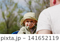 Child plays on a swing at park on sunny day with adult supervision 141652119