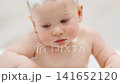 Baby enjoys bath time with foamy soap in a playful moment 141652120